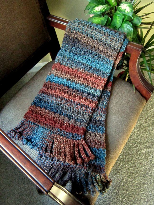 a crocheted blanket sitting on top of a chair next to a potted plant