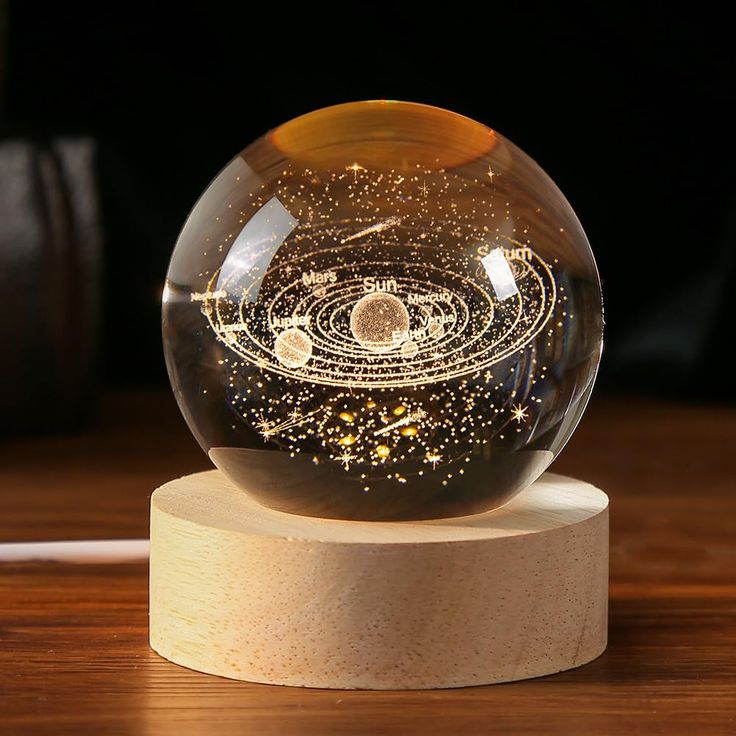 a glass ball with an image of the solar system in it on a wooden stand