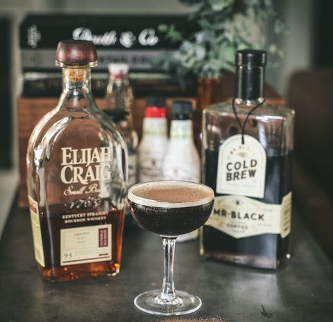 a bottle of liquor sitting next to a glass filled with liquid and another bottle in the background