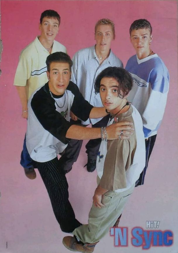 a group of young men standing next to each other in front of a pink background