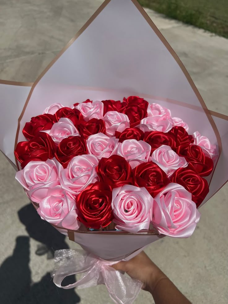 a bouquet of red and pink roses is being held up by someone's hand