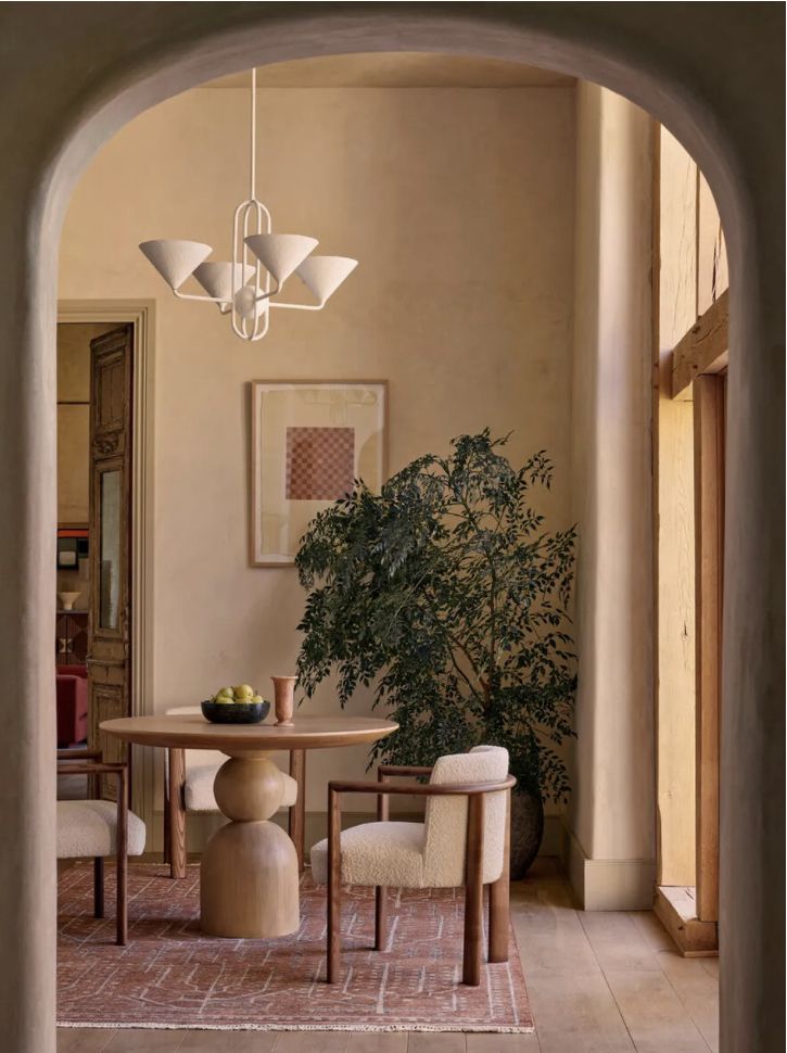 an archway leads into a dining room with chairs and a table in between two arches