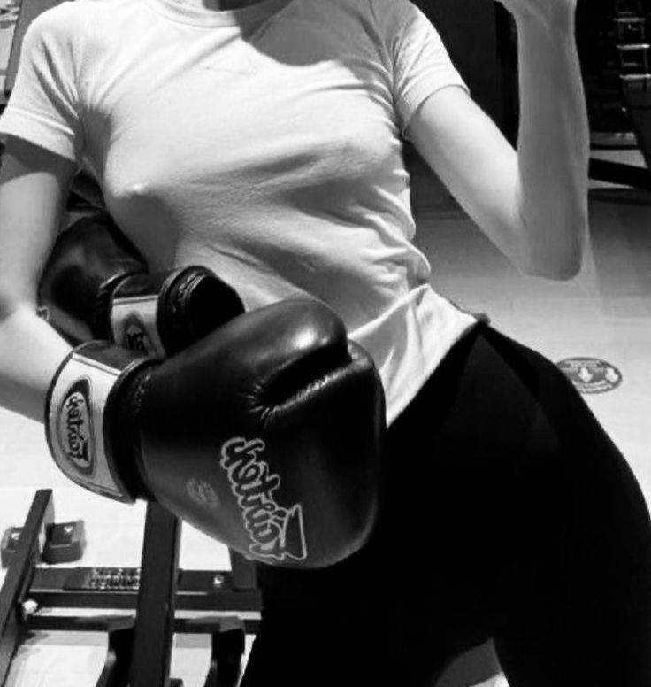 a woman sitting in a chair with boxing gloves on