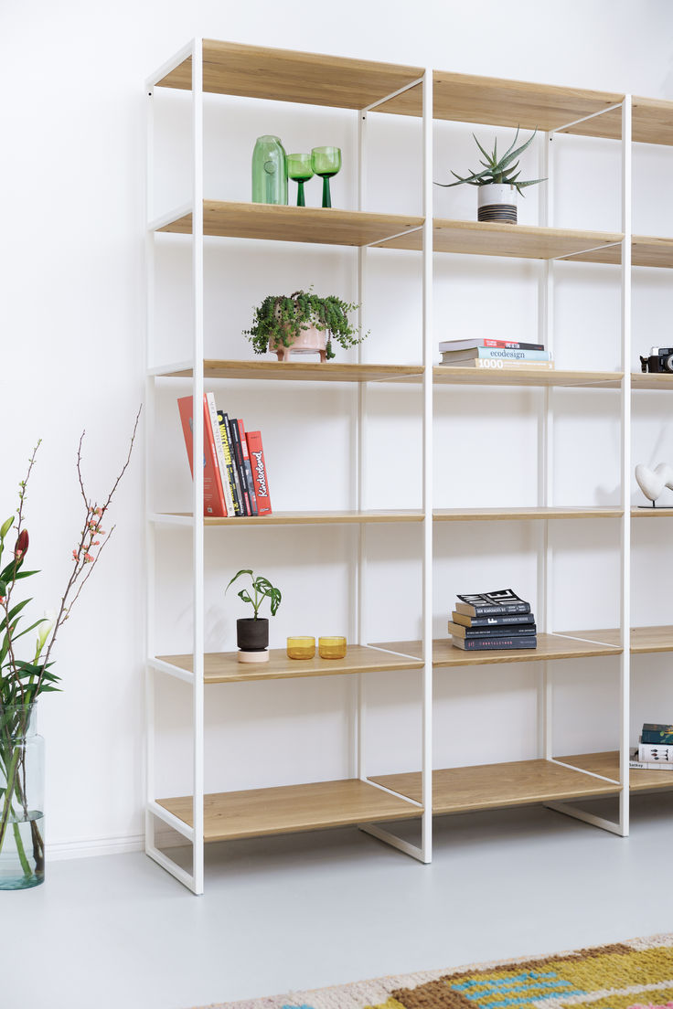 a white book shelf filled with lots of books and vases on top of it