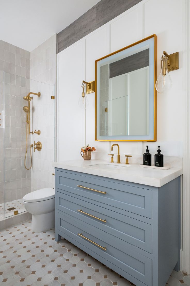 a bathroom with blue cabinets and gold accents