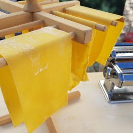 some yellow towels are hanging from a clothes line on a wooden rack next to a pasta maker