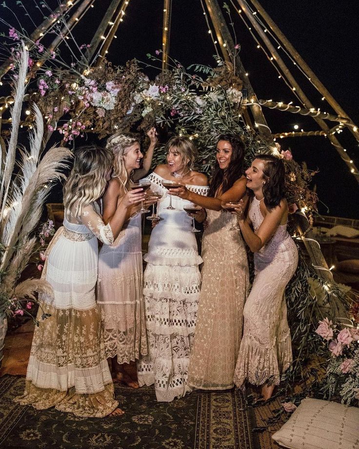 four women standing around each other in front of a gazebo with lights on it