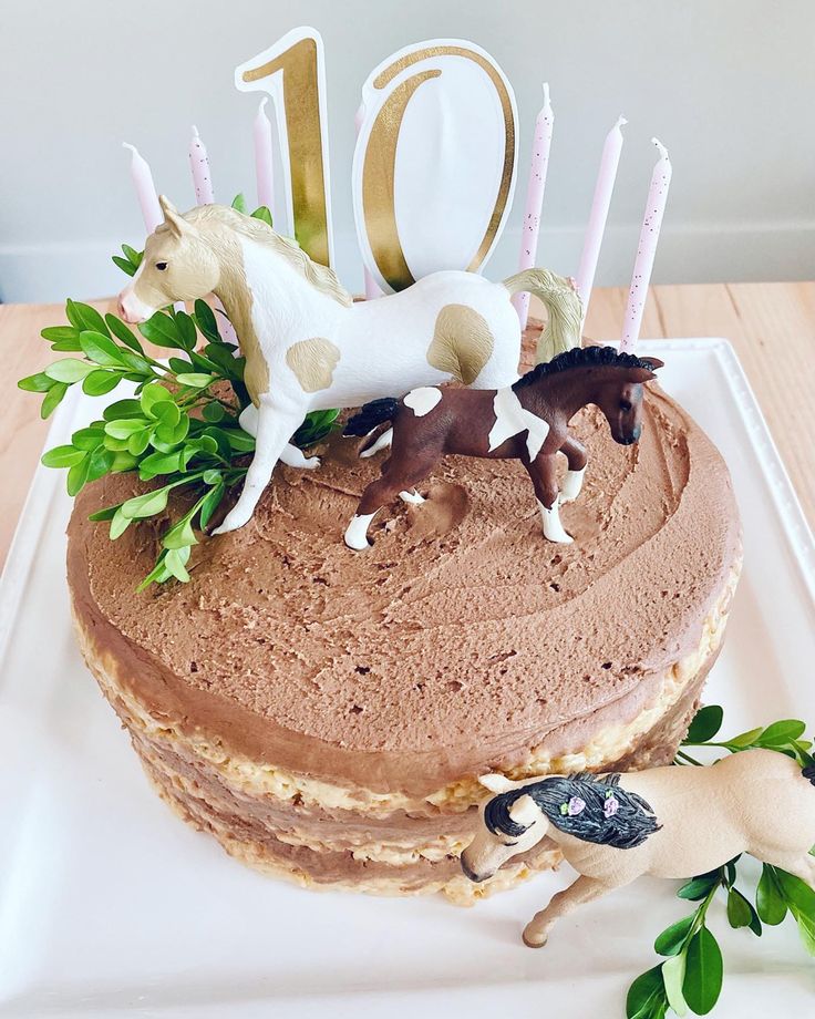 a birthday cake with two horses on top and candles in the shape of number 10