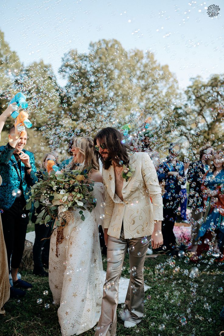 a bride and groom are walking through bubbles