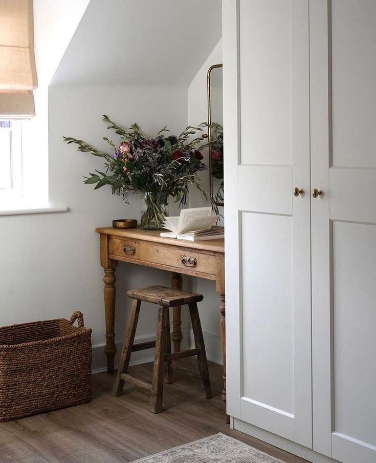 a room with white walls and wooden flooring has a plant on top of the desk