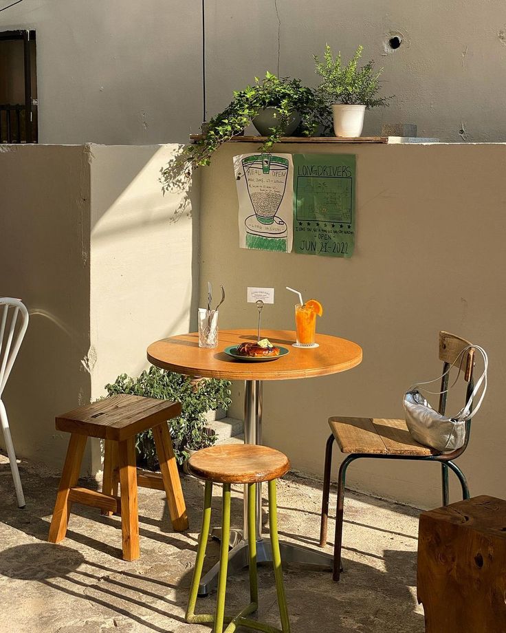 an outdoor table with three chairs around it and a potted plant on the wall