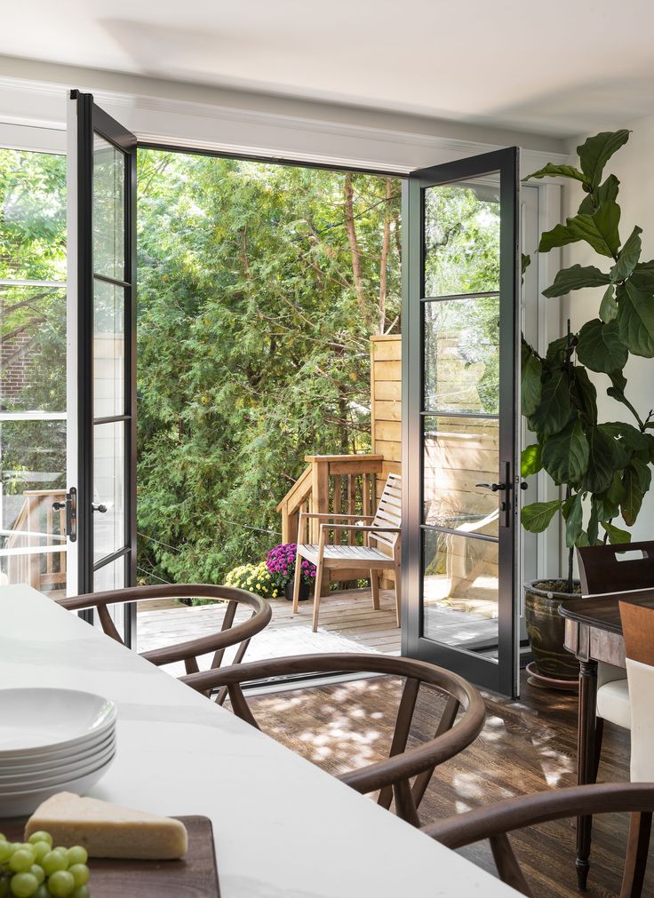 an open patio door leading to a deck with chairs and table in the foreground