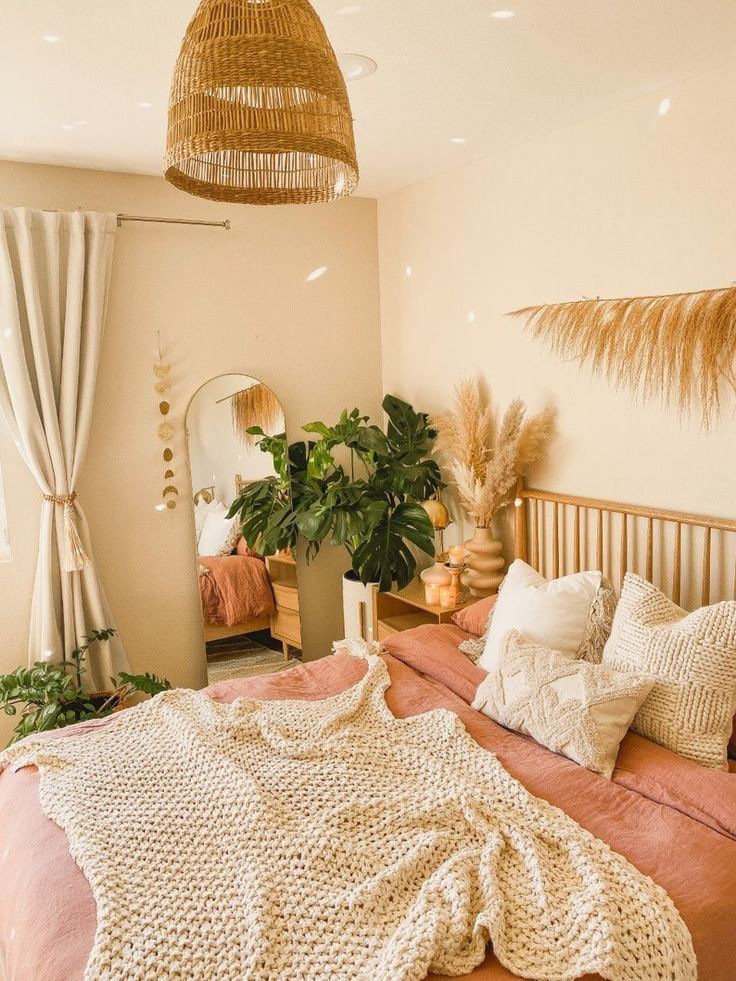 a bed with blankets, pillows and plants in a room that looks like it has been decorated