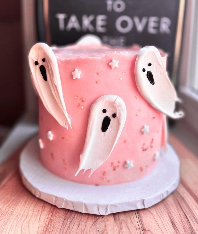 a pink cake with ghost decorations on it