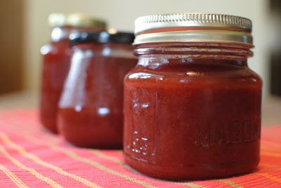 three jars filled with red sauce sitting on top of a table