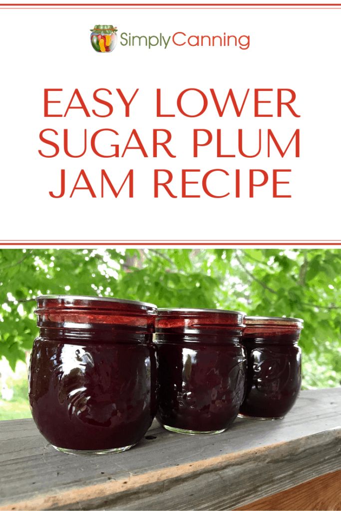 three jars filled with jam sitting on top of a wooden table in front of trees