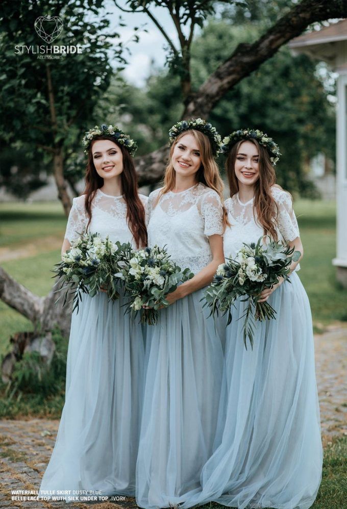 three bridesmaids in blue dresses with flowers on their head and bouquets around their necks