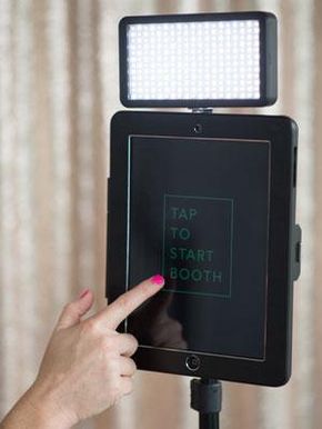 a person is pointing at the top of a light on a tripod with their finger