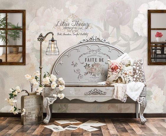 a white bench sitting on top of a hard wood floor next to a wall covered in flowers