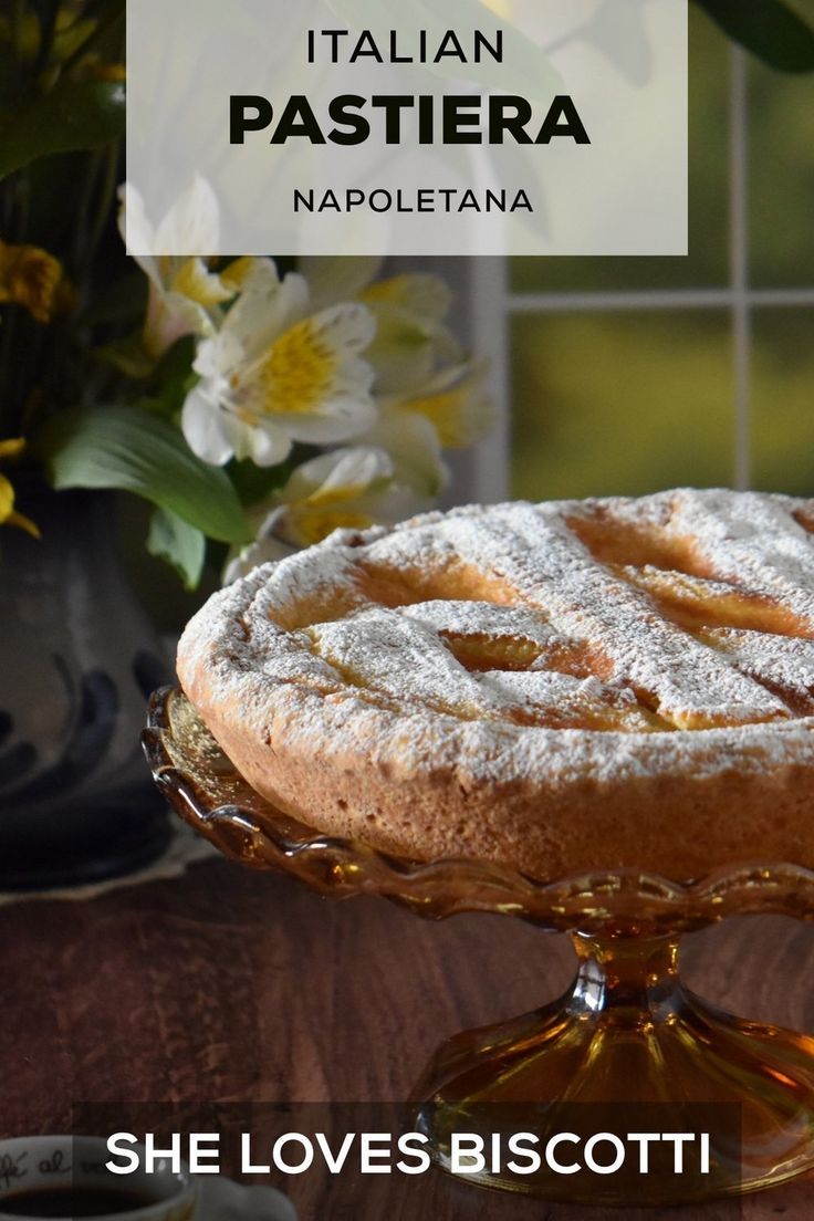 a cake with powdered sugar on top sitting on a table next to some flowers