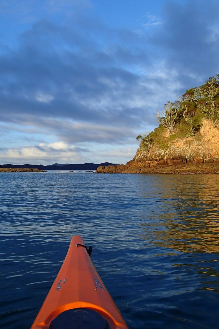 an orange kayak is in the water near a small island