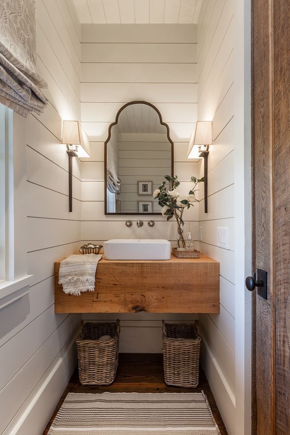 a bathroom sink sitting under a mirror on top of a wooden counter next to a door