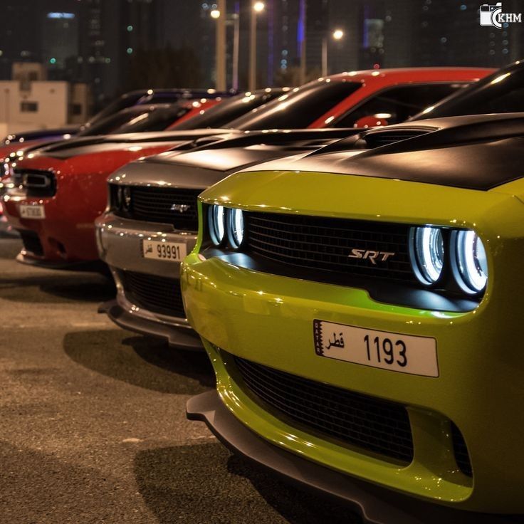 a row of cars parked next to each other in a parking lot at night time