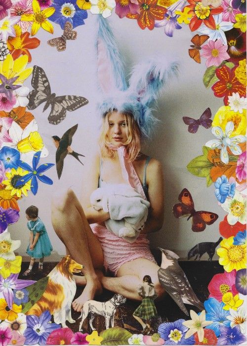 a woman sitting on top of a table surrounded by birds and flowers in front of a wall