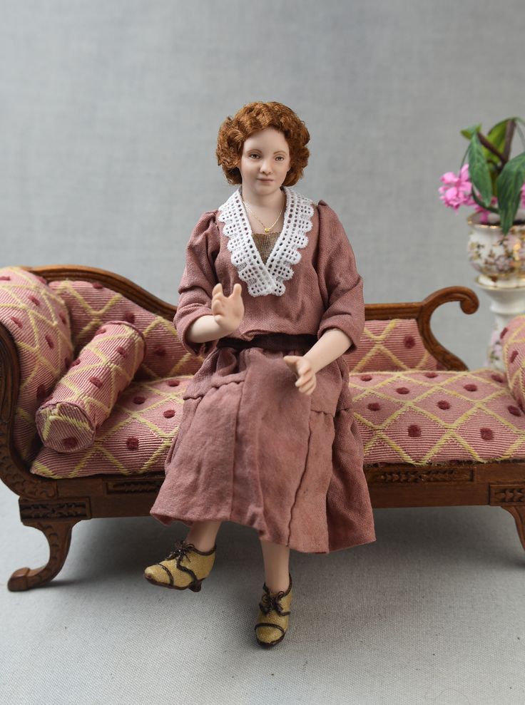 a doll is sitting on a couch in front of a potted plant and vase