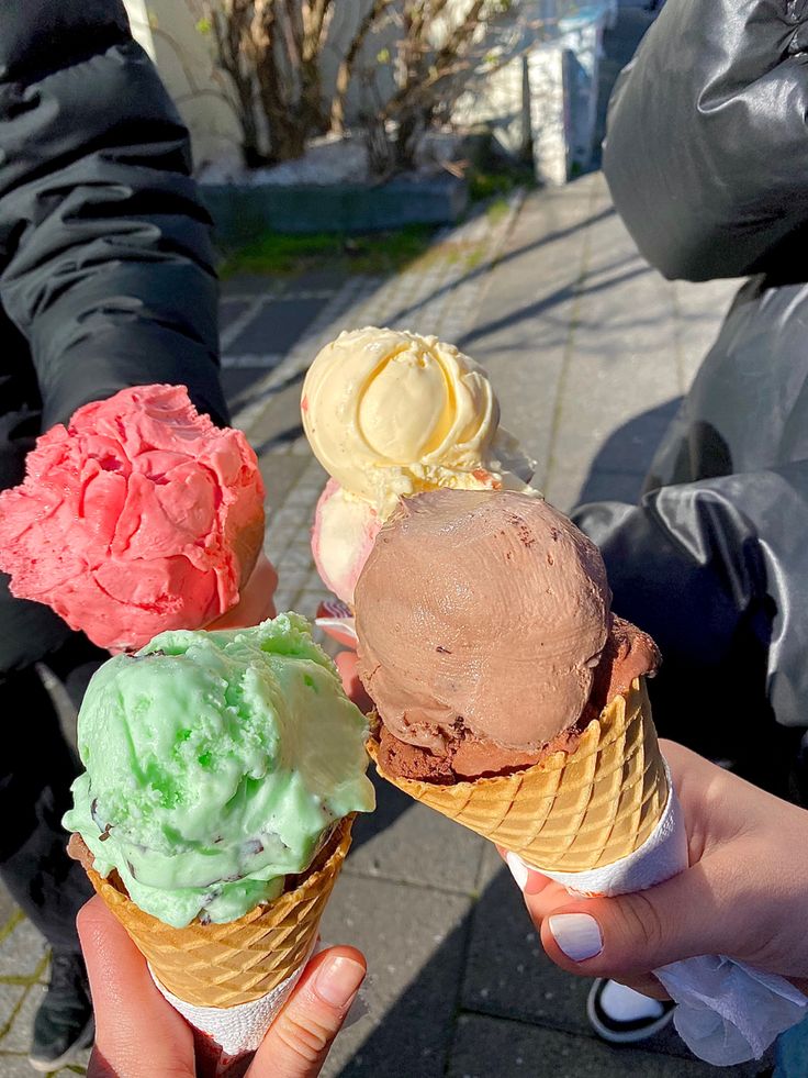 three ice cream cones are being held in their hands