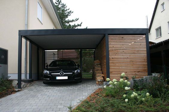 a car is parked in the garage next to some flowers and plants on the sidewalk