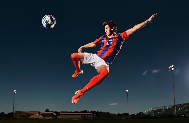 a soccer player is in mid air with the ball above his head as he kicks it