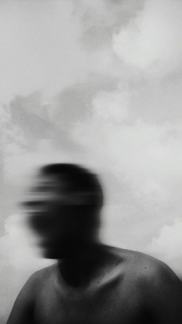 a blurry image of a man's head and torso against a cloudy sky