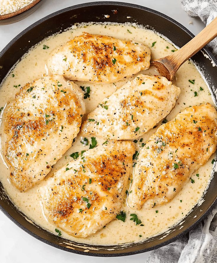 some chicken is cooking in a skillet with gravy on the side and bread