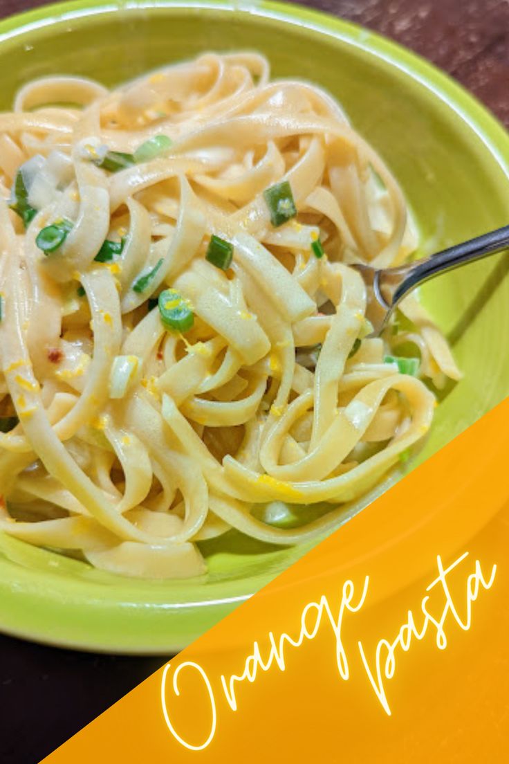 a green bowl filled with pasta and sauce on top of a wooden table next to a yellow plate