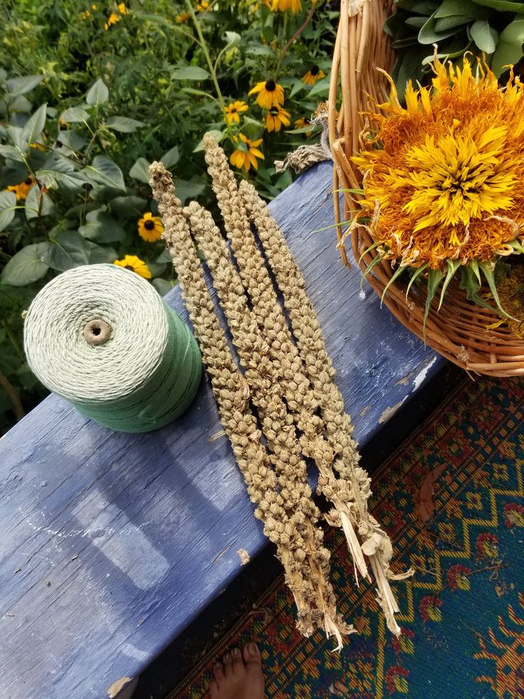 three bundles of twine sitting on top of a wooden table next to flowers and yarn