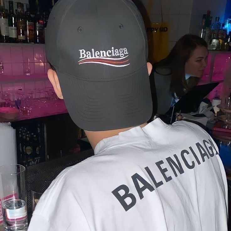 the back of a man wearing a ball cap in front of a bar filled with people