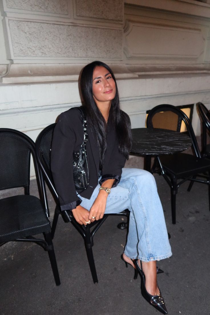 a woman sitting on top of a chair in front of a table with chairs around it