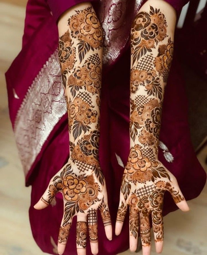 a woman's hands with hennap on her arm and hand, decorated with flowers