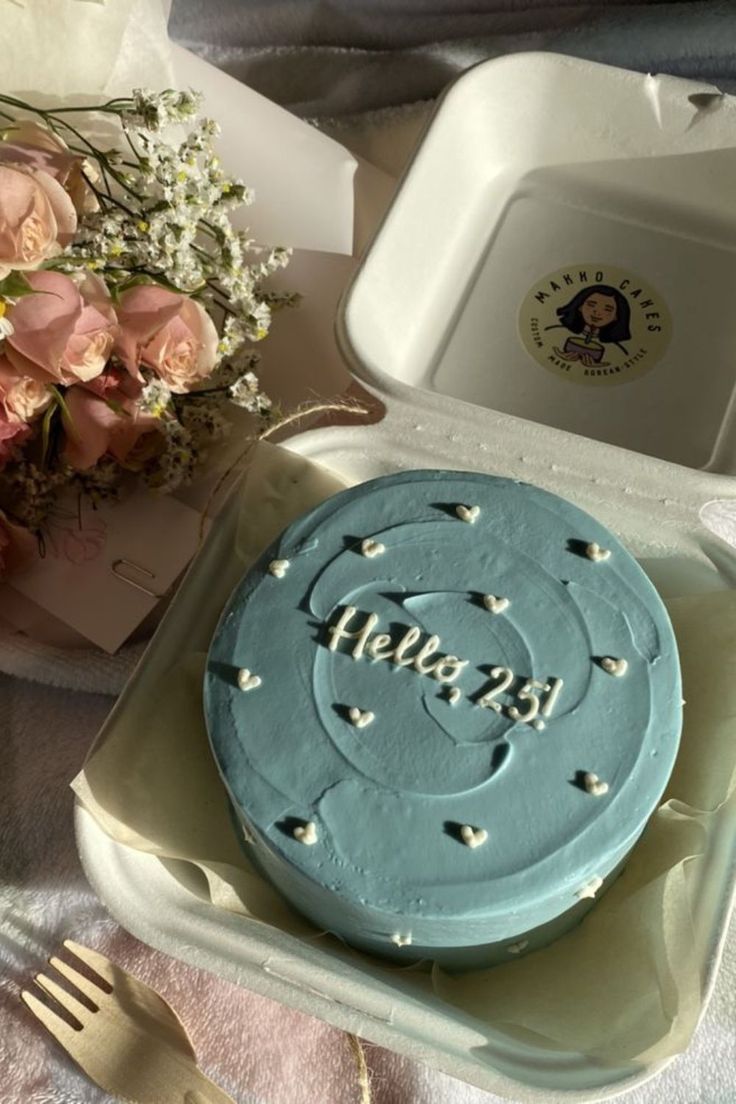 a blue cake sitting on top of a table next to a bouquet of pink roses