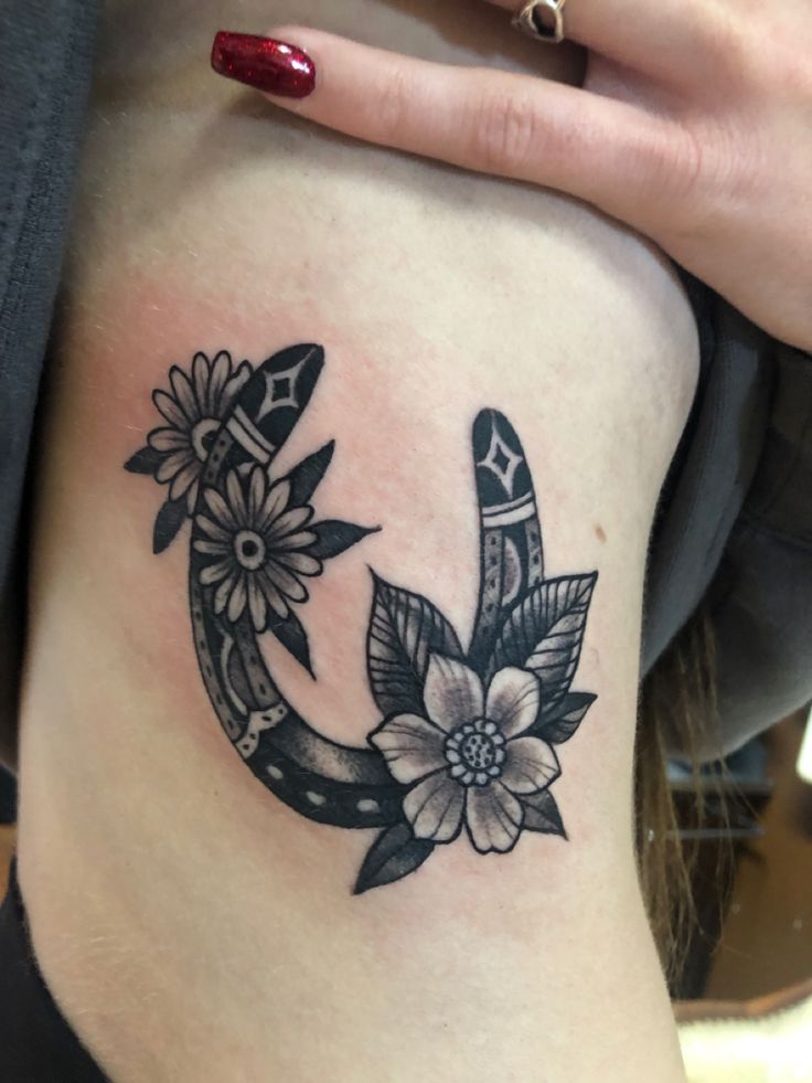 a woman's thigh with an anchor and flowers tattoo on her side ribcage