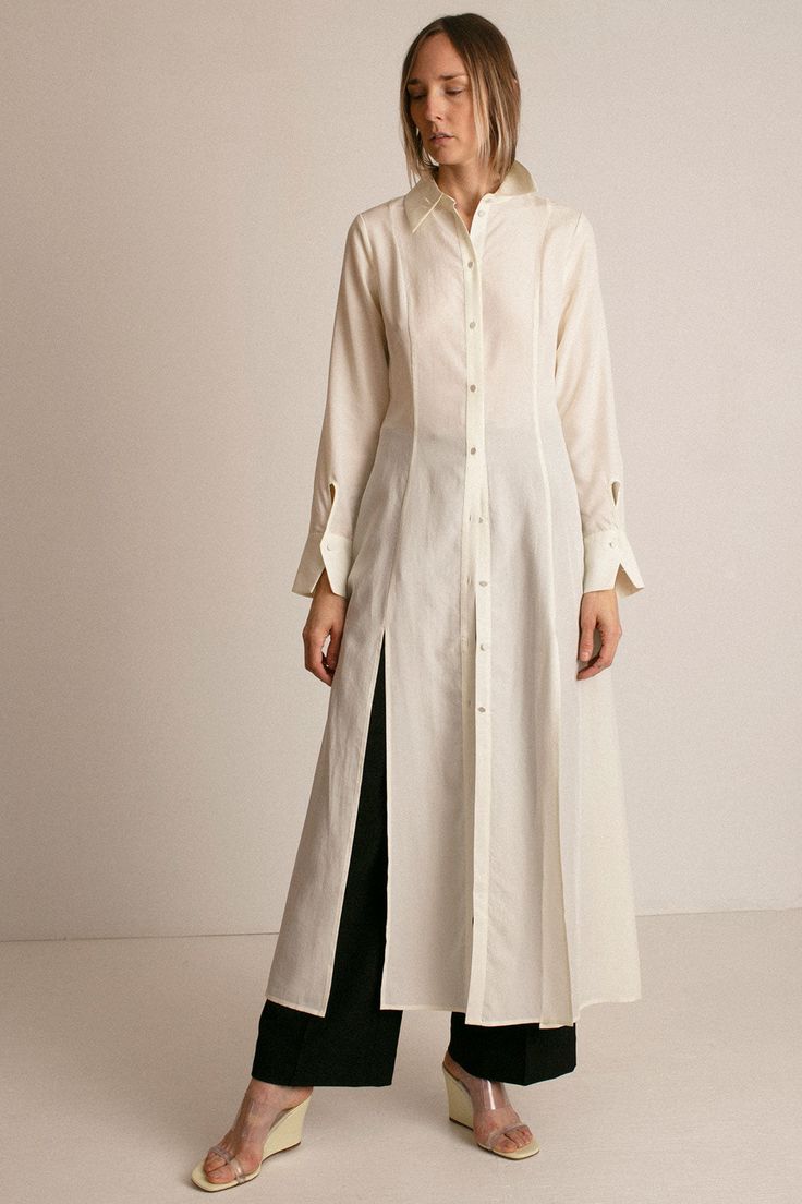 Maxi shirt dress in ivory lyocell poplin. Shirt collar. Front placket with fabric covered buttons. Princess seaming at front and back. Full skirt with front slits at hem. Long sleeves with front facing cuff. Keyhole closure at cuff. Slightly sheer. Ella is 6' tall, 35" bust, 26" waist, 36" hip, and is wearing a size S. Maxi Sleeves Design, Long Shirt Pattern, Modest Shirts For Women, Cuff Design Sleeve, Long Shirt Ideas, Long Button Down Shirt Outfit, Cuff Sleeves Kurti, Vest With Long Skirt, Long Shirt Dress Outfit