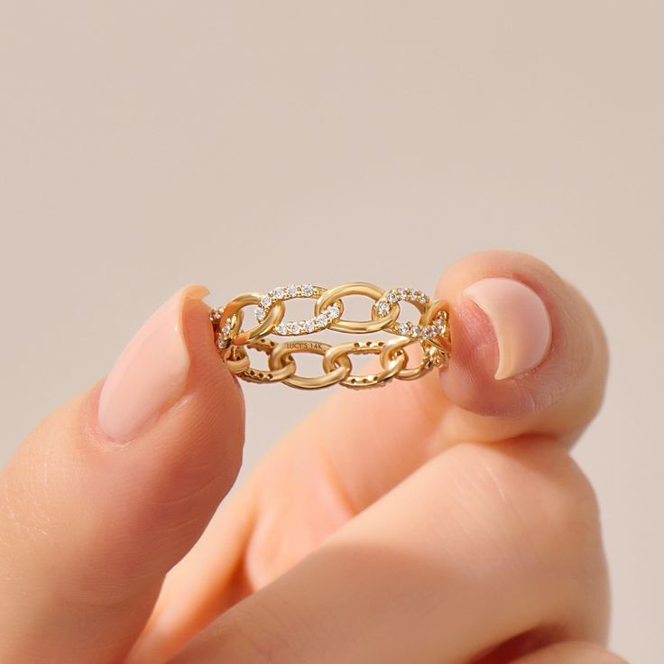 a woman's hand holding a gold ring with diamonds