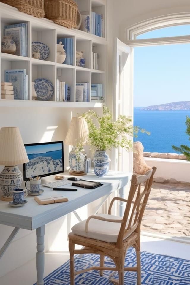 a desk with a computer on top of it in front of a window overlooking the ocean