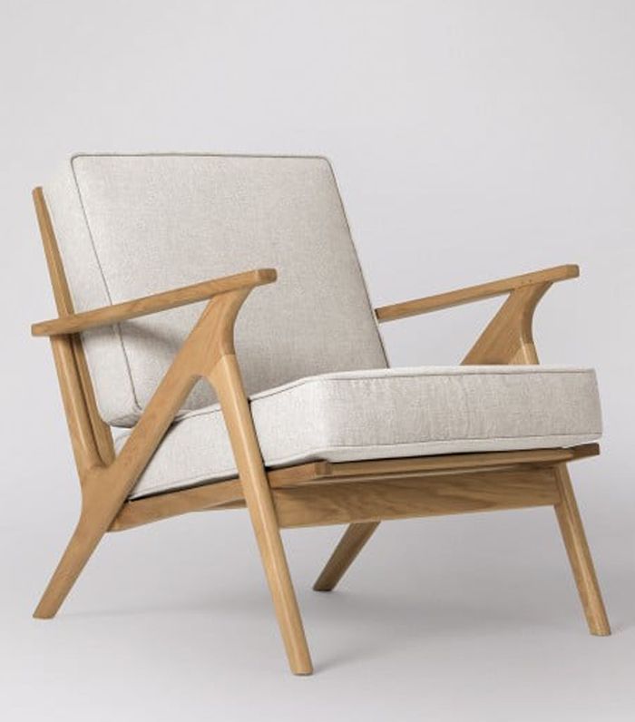 a wooden chair with a white cushion and armrests, on a gray background