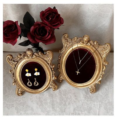 two gold framed pictures with red roses in the background and one has a necklace on it