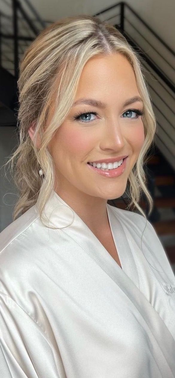 a woman with blonde hair and blue eyes smiles at the camera while wearing a white robe