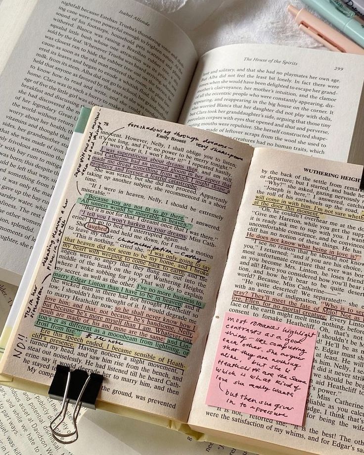 an open book with sticky notes attached to the pages and two pens on top of it