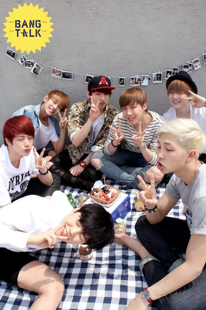 a group of young men sitting on top of a bed next to each other with their fingers in the air