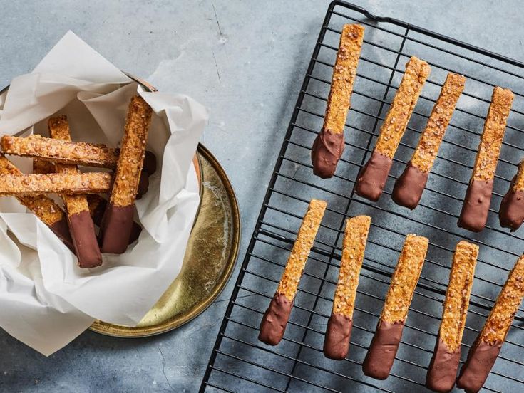 some food is sitting on a metal rack next to a cooling rack with bread sticks in it